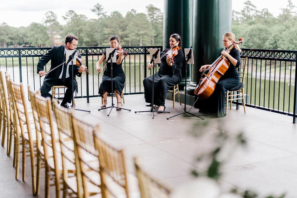 Photo of musicians playing on veranda during wedding