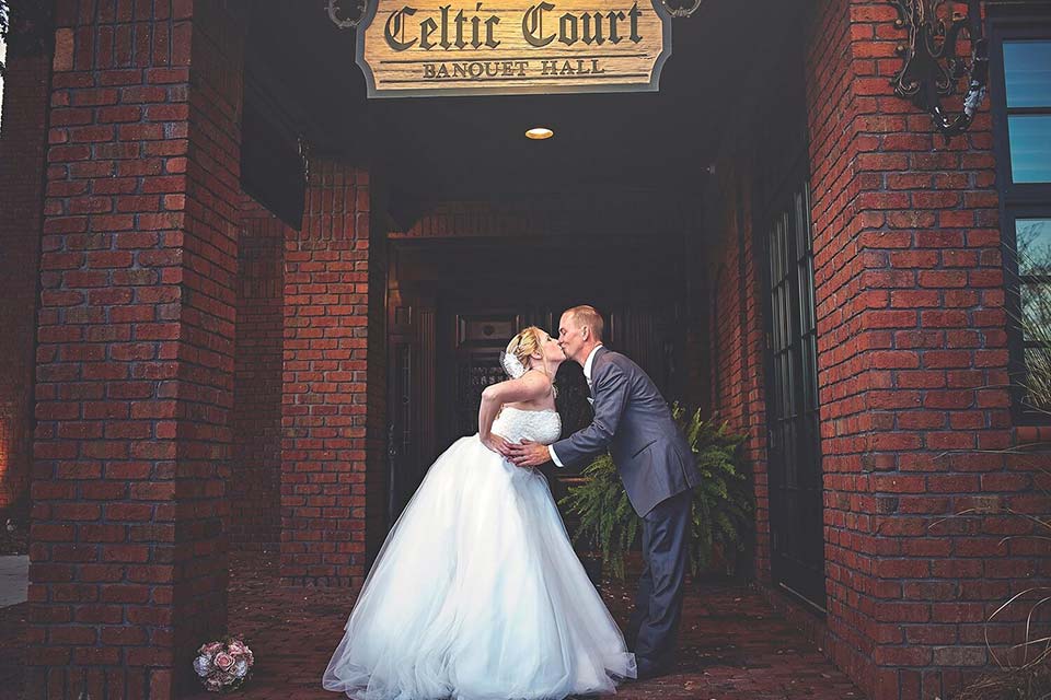 Photo of bride and groom kissing in front of an entryway
