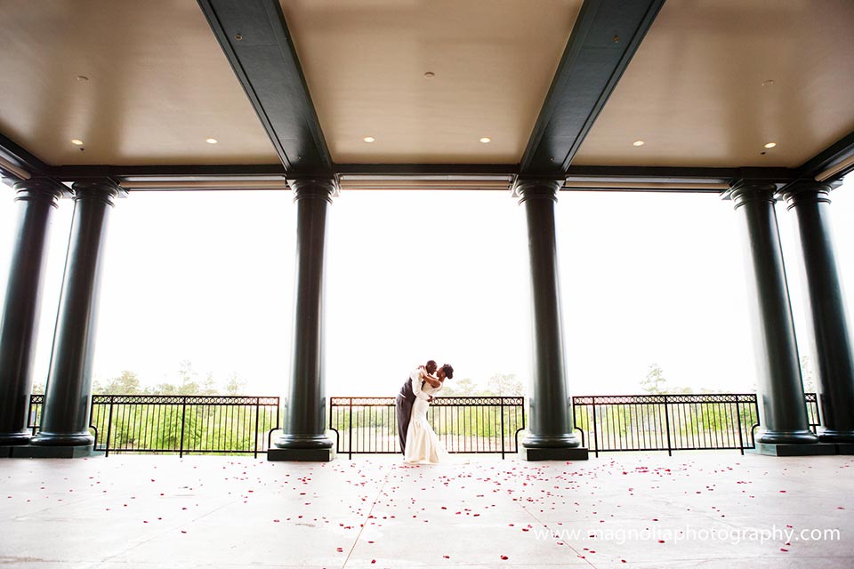 Photo of bride and groom dancing embracing on a balcony with scattered rose petals
