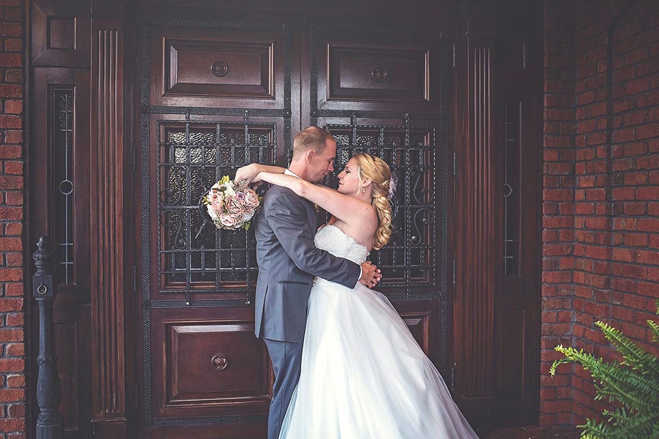 Photo of bride and groom embracing in front of a wooden door