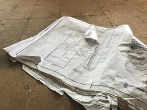 Photo of tattered blueprints on plywood floor