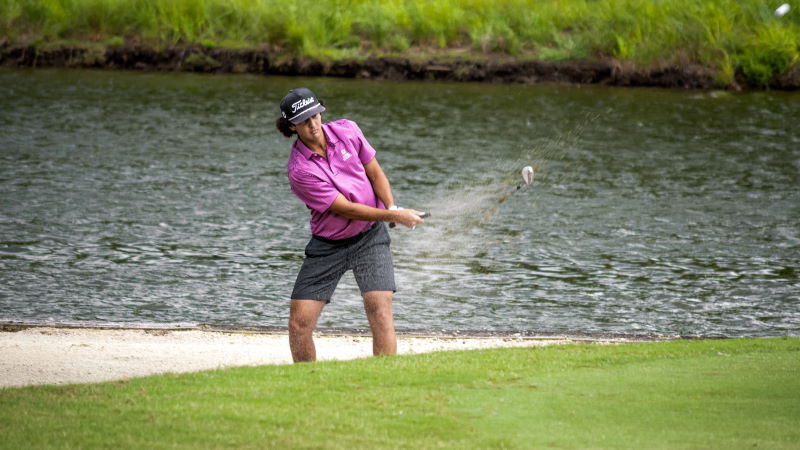 man hitting golf ball from sand