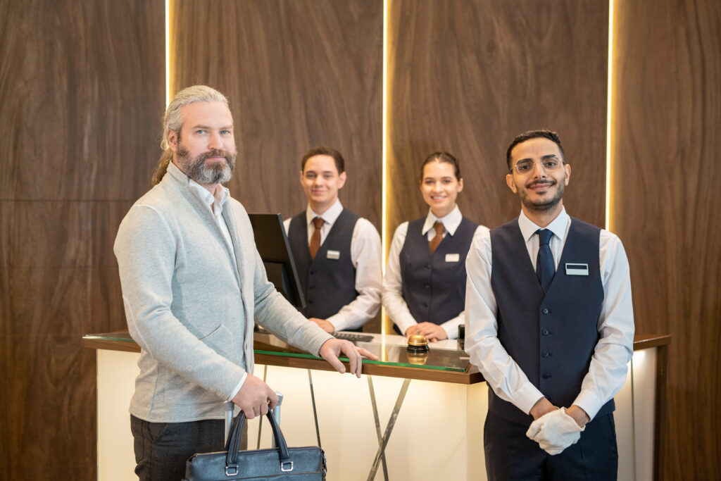 Hotel staff and mature male traveler standing by reception counter