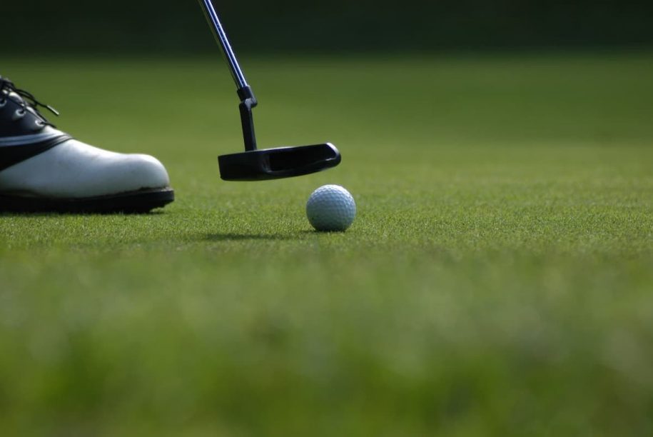 man putting golf ball in the hole